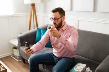 Evde yakışıklı bir adam akıllı telefondan sanal bir doktorla konuşuyor ve bazı ilaçlar gösteriyor. 