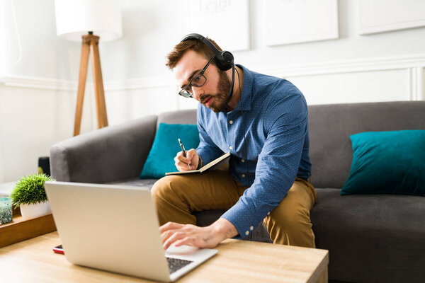 Занятый кавказский мужчина и ассистент, делающий заметки во время онлайн-видеозвонка с боссом, находясь дома