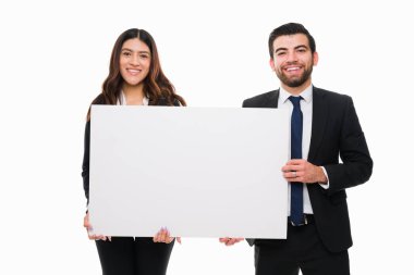 Neşeli iş ortakları ellerinde fotokopi yeri ile boş bir tabela tutuyorlar ve hukuk firmaları için reklam yaparken gülümsüyorlar.