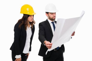 İnşaat işlerinde mimar planlarına bakarken güvenlik miğferi takan mühendisler.