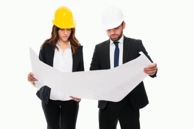 Güvenlik kaskı takan profesyonel mühendisler ve yeni bir iş binasının inşaat planları üzerinde çalışıyorlar.