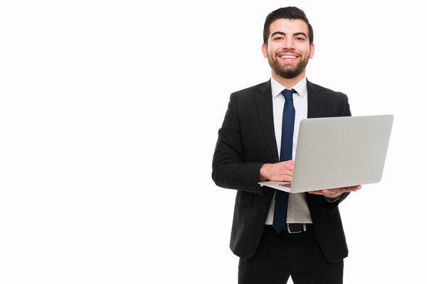 Successful young lawyer. Attractive businessman working on his laptop and smiling to the camera next to copy space