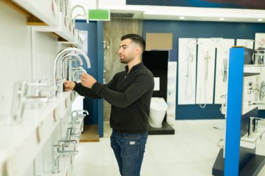 Güzel bir mobilya dükkanından paslanmaz çelik mutfak musluğu almayı seçen yakışıklı bir genç.