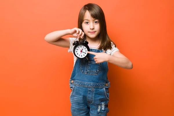 Little Girl Holding Alarm Clock Pointing Current Time While Looking — Stock Photo, Image