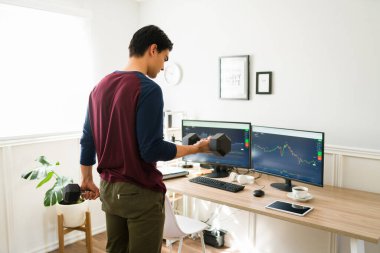 Ofisteki borsaya yatırım yaparken egzersiz yapan ve ağırlık kaldıran aktif bir adamın arka görünüşü