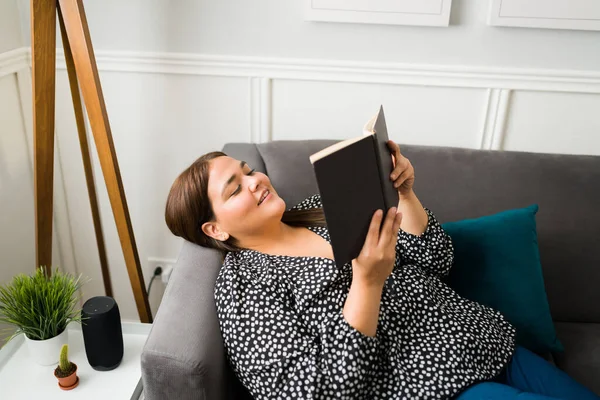 躺在沙发上看书的年轻女人松了口气 快乐肥胖的女人享受着新奇的生活 — 图库照片