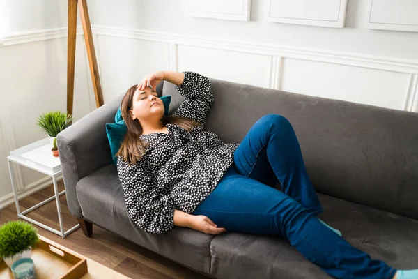 可悲的胖女人在沙发上休息时感到疲惫和沮丧 患有头痛的压力过重的妇女 — 图库照片