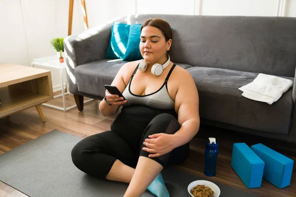 西班牙美女胖女人在家锻炼后 一边用智能手机发短信 一边休息 — 图库照片
