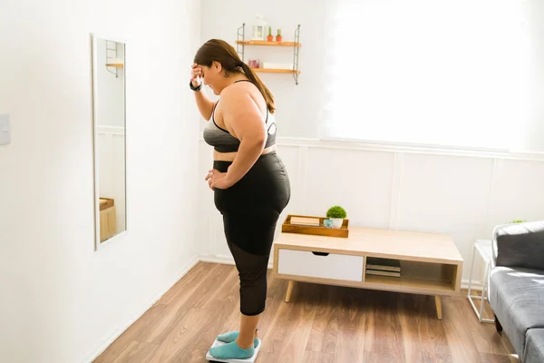 这是不健康的 忧心忡忡的肥胖女人用秤称自己的体重 — 图库照片