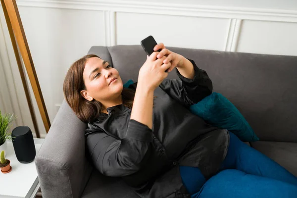 迷人的拉丁女人一边微笑 一边用智能手机发短信和查看社交媒体 肥胖妇女愿意和朋友出去 — 图库照片