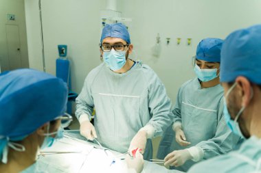 Cerrahi maske takan ve ameliyat yaparken göz teması kuran beyaz erkek cerrah. 