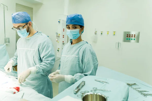 在手术室工作时穿着蓝色刷子看着相机的惊慌失措的女外科医生的画像 — 图库照片