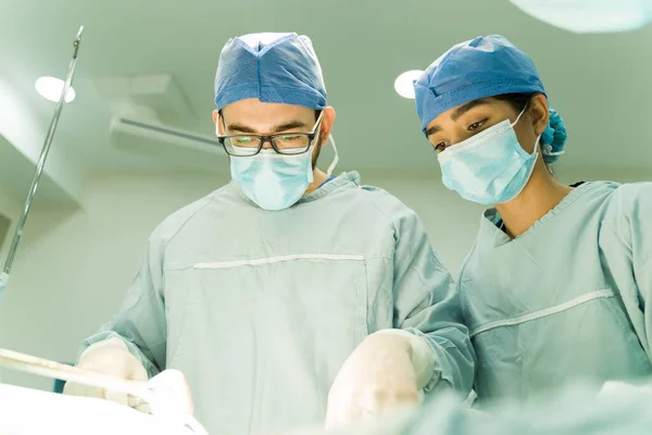 在医疗护士的帮助下进行外科手术的带手套和刷子的高加索外科医生 — 图库照片