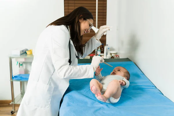 病院で健康診断をしながら可愛い赤ちゃんと遊ぶ幸せな女性小児科医 — ストック写真