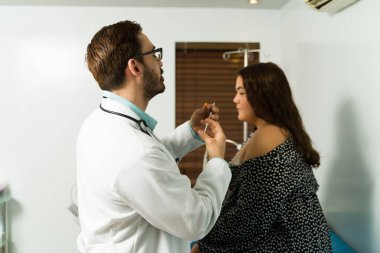 İlaç enjeksiyonu için şırınga hazırlayan profesyonel bir doktorun arka görüşü. Genç bir kadın aşı oluyor.