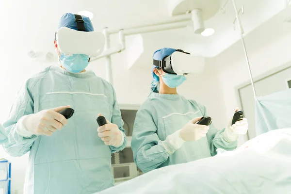 Surgeons Operating Room Using Controllers Virtual Reality Glasses While Performing — ストック写真