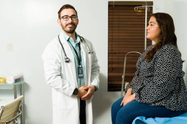 Bir hastanın sağlık sorunlarını tedavi ederken gülümseyen yakışıklı doktor. 