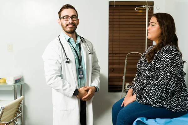 Bir hastanın sağlık sorunlarını tedavi ederken gülümseyen yakışıklı doktor. 