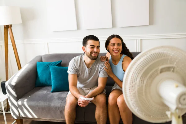 Beautiful Couple Smiling While Using Electric Fan Home Cool Hot — стоковое фото
