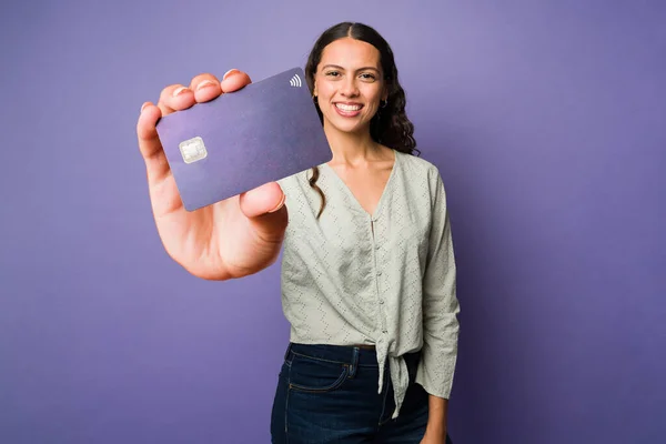 一个年轻貌美的女子在工作室前展示一张紫色的大信用卡的肖像 — 图库照片