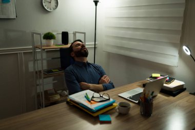 Çok çalışan yorgun bir adam son teslim tarihinden dolayı evde çalışırken masasının önünde uyuyor.