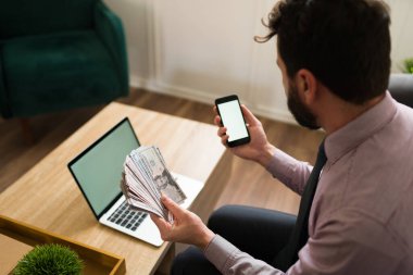 Bir sürü parası olan beyaz bir adamın faturaları öderken internet bankasını akıllı telefonunda kullanmasının arka görüntüsü.