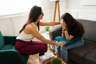 Depresyondaki kız terapi seansı sırasında yüzünü kapatıp ağlıyordu. Profesyonel psikolog genç bir hastayı rahatlatıyor.