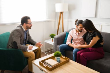Çift terapisi sırasında mutlu bir karı kocaya evlilik tavsiyesi veren profesyonel bir psikolog.