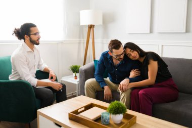 Çekici bir çift, çiftler terapisi sırasında evlilik sorunlarını çözerken birbirlerine sarılıyorlar.