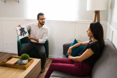 Erkek psikolog terapi sırasında kadın bir yetişkin hastaya teşhis koymak için bir hata testi gösteriyor. 