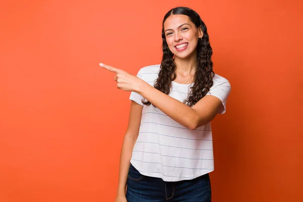 Portrait Attractive Young Woman Smiling Pointing Copy Space Orange Studio — Fotografia de Stock