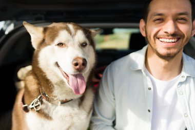 Mutlu İspanyol bir adamın portresi ve köpeğinin araba bagajında dinlenirken mola vermesi.