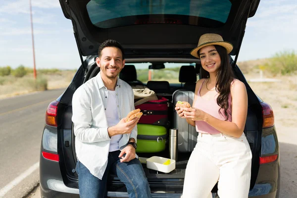 Neşeli çift yol kenarında arabada yemek yerken birlikte uzun bir yolculuk yapıyorlar.