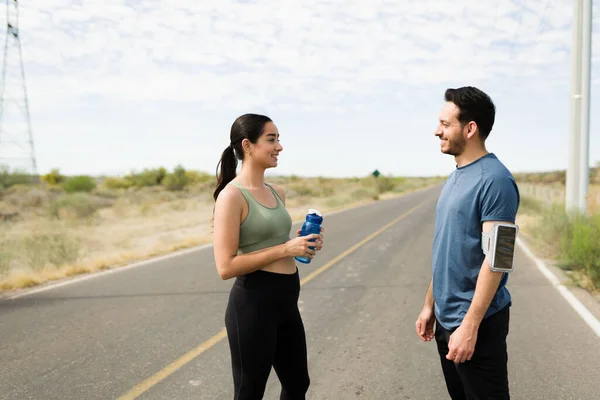 Attractive fit couple talking and feeling happy after finishing running together outdoors