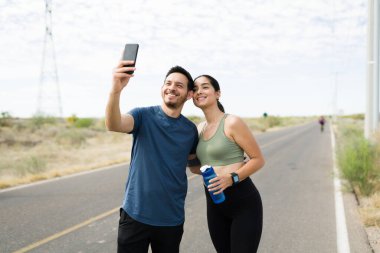 Yakışıklı genç çift birlikte selfie çekiyor ve dışarıda koşmayı bitirdikten sonra sosyal medyada paylaşıyorlar.