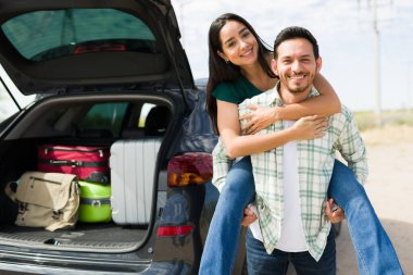 Beautiful happy couple having fun during a road trip. Latin man piggybacking his girlfriend