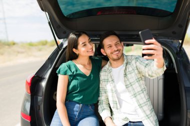 Neşeli İspanyol çift sosyal medya için selfie çekerken birlikte bir yolculuğa çıkıyorlar. 