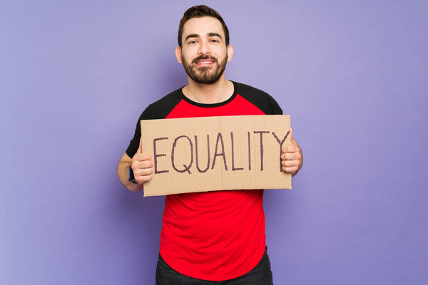 Handsome man in his 30s supporting sexual and gender equality while holding a protest sign 
