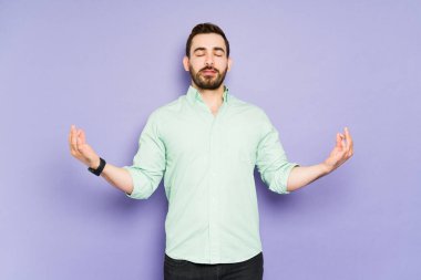 Rahatlamış genç adam biraz stres atmak için nefes egzersizi yapıyor ve meditasyon yapıyor.