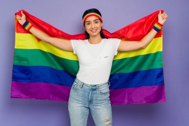 Neşeli genç bir kadın, LGBT yürüyüşü sırasında gey haklarını desteklemek için gökkuşağı bayrağı kullanıyor. 