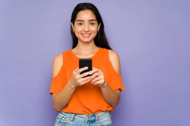 Gülümseyen genç bir kadın arkadaşlarına ve ailesine mesaj atıyor ve sosyal medyada yeni akıllı telefonuyla paylaşıyor. 