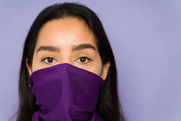 Close up of a feminist woman wearing a purple bandana on her face while protesting violence against women