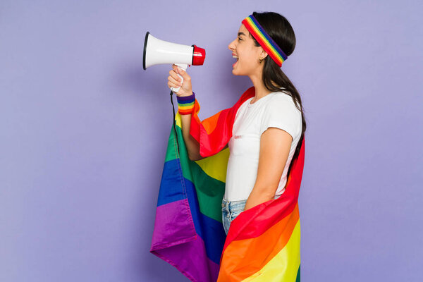 Side view of a young woman screaming with a megaphone and giving a gay rights message during a protest 