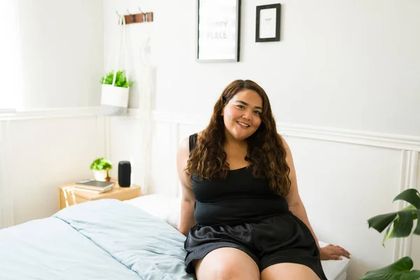 快乐的大年轻女人坐在床上 西班牙肥胖女人在漂亮的卧室里享受着一天的闲暇 — 图库照片