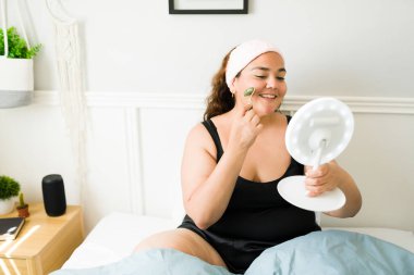 Mutlu koca kadın cilt bakımını yapıyor ve yüzündeki kırışıklıkları önlemek için yeşim bir silindir kullanıyor. 