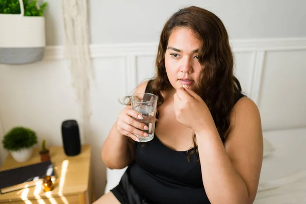 肥胖妇女服用含有一杯水的药丸治疗慢性疾病 大女人吃维生素是为了更好的健康 — 图库照片