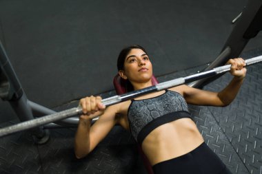 Spor salonunda göğüs presi yapan genç bir kadının yüksek açısı. Spor salonu antrenmanı ve halter.