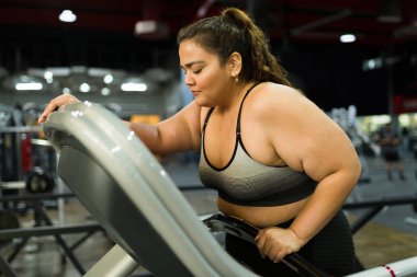 Yorgun şişman kadın koşup spor salonunda egzersiz yaptıktan sonra hasta ve midesi bulanıyor.