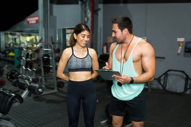 Spor salonundaki güçlü kişisel antrenör formda bir kadına spor yapmak ve sağlıklı bir plan yapmak hakkında konuşuyor. 