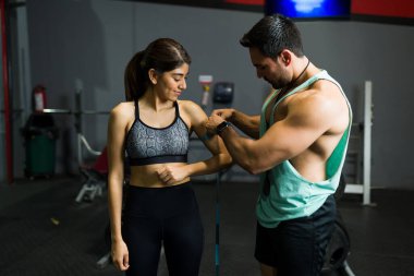 Güçlü bir fitness koçu genç ve güçlü bir kadının gelişimini kontrol ediyor. Sportif kadın spor salonunda kas geliştiriyor.